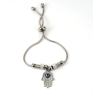 Macro detail of silver snake chain with Hamsa Hand and blue Evil Eye charm for women