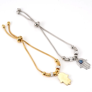 Close-up of gold and silver snake chain bracelets featuring Hand of Fatima and Evil Eye charms