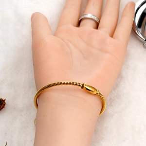 Detail eines 18K Gold Schlangenkettenarmbands mit glatter Schnalle auf weißem Plüsch