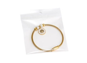 Detail eines goldenen Schlangenarmbands mit Baum des Lebens Anhänger und weißen Kristallen