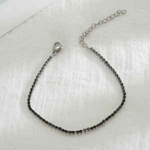 Détail du bracelet tennis argenté avec pierres de zircon noires et fermoir mousqueton
