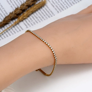 Vue détaillée d'un bracelet tennis doré pour femme serti de zircons porté sur le poignet