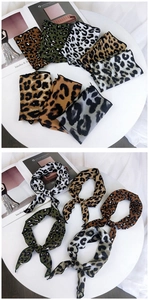 Detailed close-up of various leopard print silk neckerchiefs with glossy finish