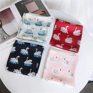 Carrés de soie élégants à motif cygne en blanc, rouge, noir et rose présentés sur table