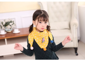 Detail of yellow knit scarf with white rabbit print and colorful plush ball pom-poms