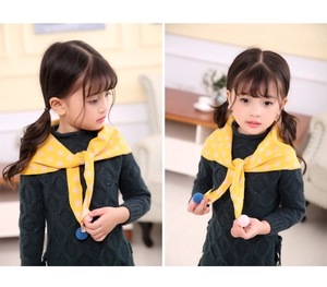 Detail of yellow knit scarf with rabbit print and colorful pom-poms for children