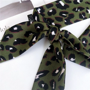 Foulard étroit léopard vert armée en polyester noué en boucle sur un livre décoratif