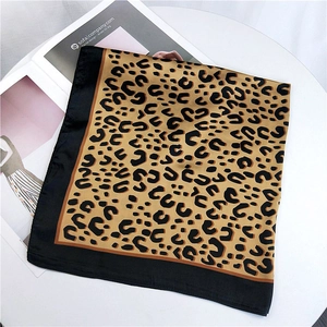Classic leopard print square silk scarf with black border on a minimalist table