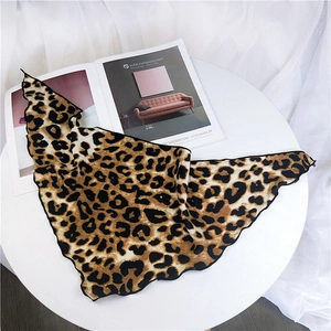 Classic leopard print silk scarf featuring delicate black wavy stitched edges on table