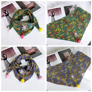 Detail of cotton triangle scarves with floral print, pom-poms, and cute bear applique