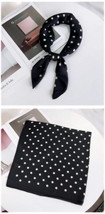 Detailed view of black and white polka dot silk scarf tied in a bow on a white background