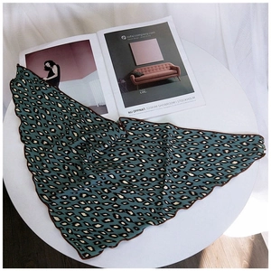 Detail of teal leopard print triangle scarf with wavy edges on a minimalist background