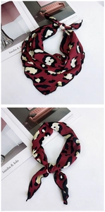 Detail of elegant leopard print silk scarf with black stitched edges and knot styling