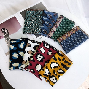 Flat lay of leopard print and geometric patterned silk scarves on white fashion magazines