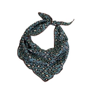 Blue leopard print triangular silk scarf with brown trim tied in a knot on white background