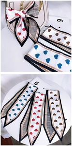 Silk-feel scarves with heart patterns used as elegant ribbon decoration on a handbag
