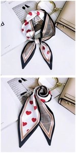 Detailed view of red heart and plaid patterns on silk twilly scarf tied on a handbag