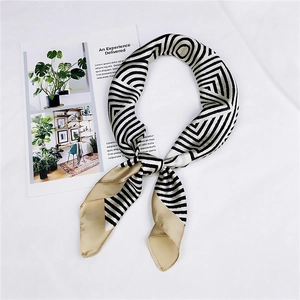 Detail of a tied silk scarf with black white geometric patterns and gold satin edges