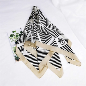 Detailed close-up of a 70cm silk scarf featuring black white geometric patterns and gold border