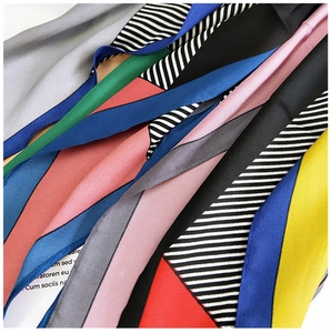 Close-up of assorted silk-satin skinny scarves featuring geometric patterns and soft textures