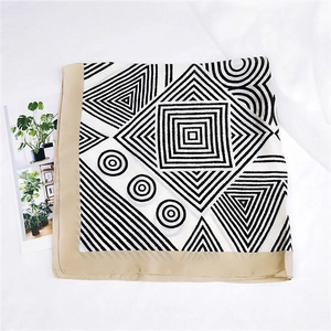 Detail of square silk scarf with black and white geometric patterns and gold satin border