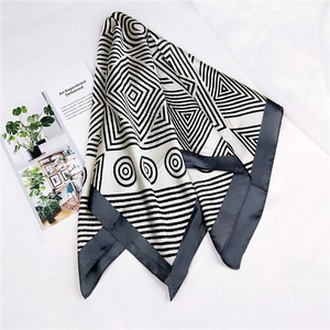 Detailed view of square silk scarf with black and white geometric patterns and smooth texture