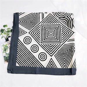 Detailed view of square silk scarf featuring black and white geometric patterns and borders