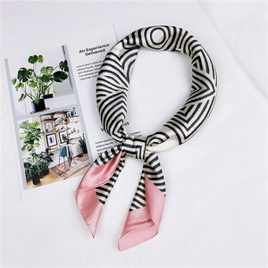 Flat lay of striped silk scarf with pink accents next to a minimalist magazine