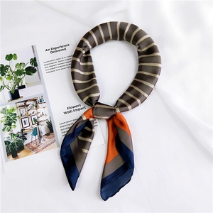 Close-up of striped silk square scarf knotted on a white fabric with satin texture