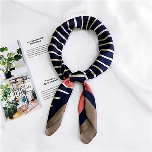 Detail of striped silk-like satin neckerchief tied in a loop on a soft white fabric background