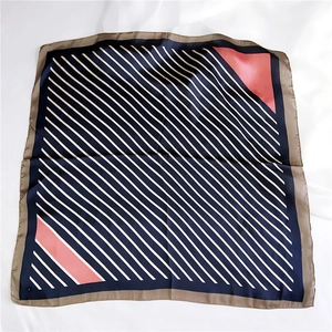 Navy blue striped square scarf with coral accents on white wrinkled background