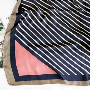 Detail of silk-like scarf with navy blue and white stripes plus soft pink geometry