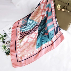 Carré de soie géométrique avec motifs paisley stylisé sur un décor de sac en cuir