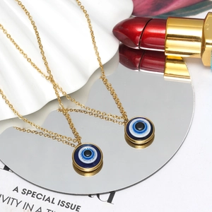 Golden Evil Eye pendant necklace on white wave board with mirror reflection detail