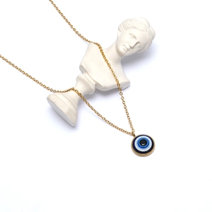 Artistic display of gold Evil Eye necklace on a white classical plaster bust statue