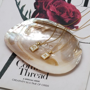 Detail of 18K gold stainless steel Leo and Gemini necklaces with white mother of pearl inlay