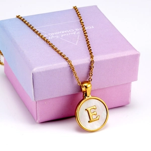 Detail of 18K gold stainless steel letter E necklace with white shell inlay in a gift box