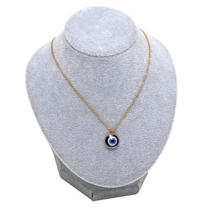 Gold evil eye necklace with blue pendant on a grey velvet display bust stand