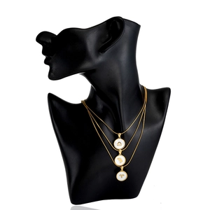 Three-layer gold snake chain necklace featuring circular zodiac shell pendants on a black bust