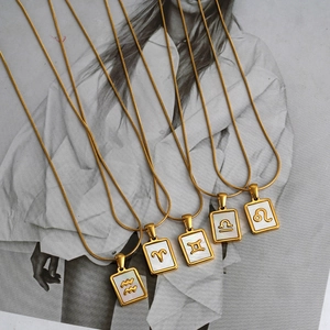Macro detail of 18K gold zodiac pendants with white mother of pearl on snake chain