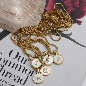 Detailed shot of 18K gold plated stainless steel letter necklaces with white shell inlay