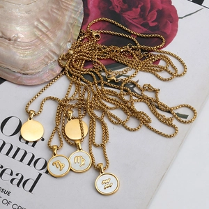 Detailed macro shot of 18K gold shell initial pendant necklace on a fashion magazine