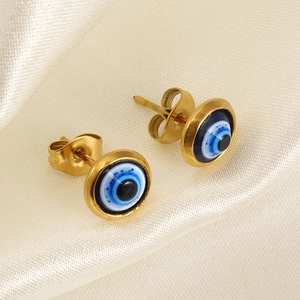 Detail shot of golden evil eye stud earrings on elegant silk background with butterfly backs