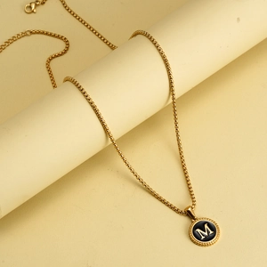 Detail of 18K gold-plated M letter coin pendant necklace with black enamel inlay