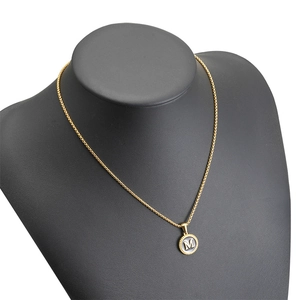 18K gold plated stainless steel necklace with letter M pendant on a black bust