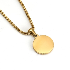 Macro shot of 18K gold plated box chain and circular brushed metal pendant on white base