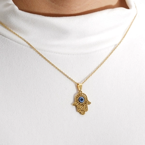 Hamsa Hand ketting met boze oog hanger gedragen op een witte coltrui trui