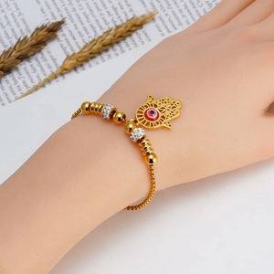 Hamsa Hand and Evil Eye gold bracelet worn by a model in a stylish lifestyle setting
