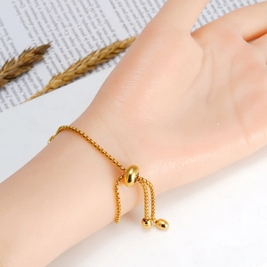 Detail of adjustable gold box chain bracelet with sliding bead closure on wrist