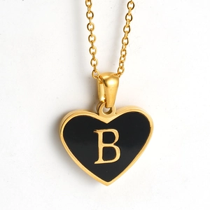 Close-up of golden heart pendant with black inlay and letter B on a delicate O-chain